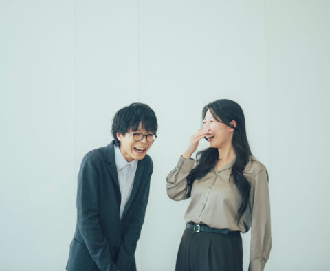 オフィスで楽しそうに笑い合う同僚の男女