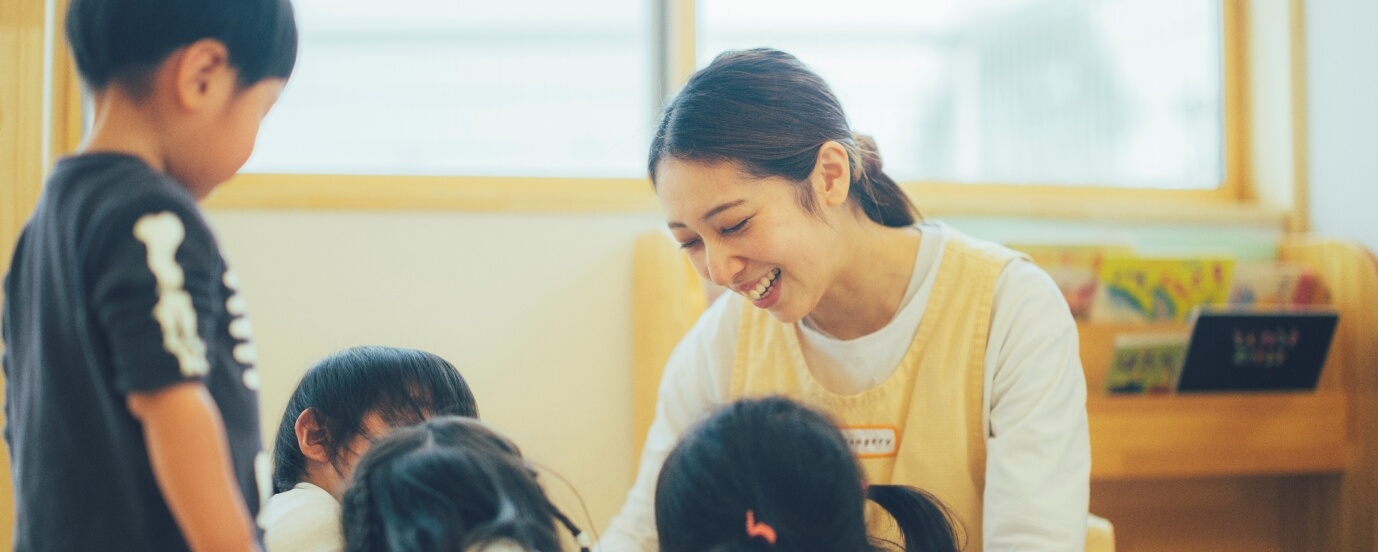 たくさんの子どもたちと遊ぶ女性保育士の写真