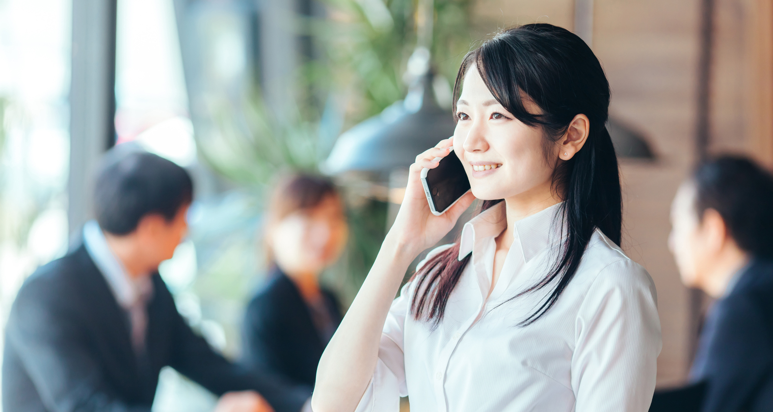営業, スマートフォンで営業の電話をする女性従業員の写真