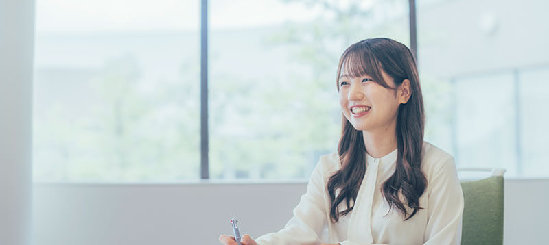 明るい窓際で打ち合わせに参加し笑顔を見せる女性