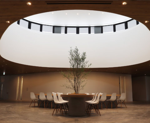 円形の天窓から光が差し込むホール。中央にはシンボルツリーを囲む円形テーブル。