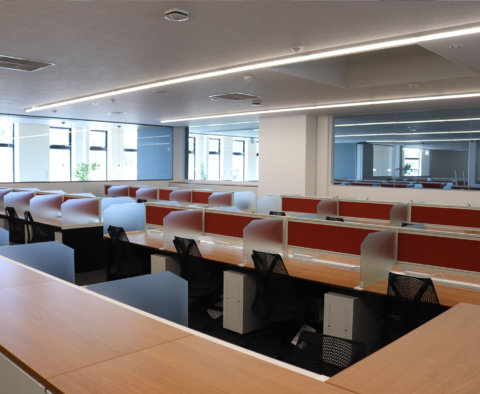 赤いパネルがアクセントの、整然と並んだ集中しやすいデスクエリア。